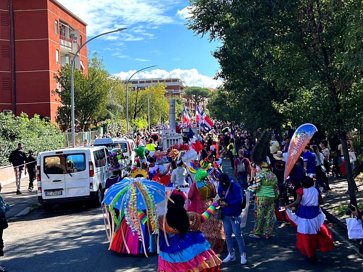 Dominican cultural parade participants celebrating outdoors with flags and colourful costumes.